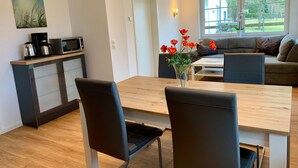 Une cuisine moderne avec un coin repas, une machine à café et un vase rempli de fleurs rouges.