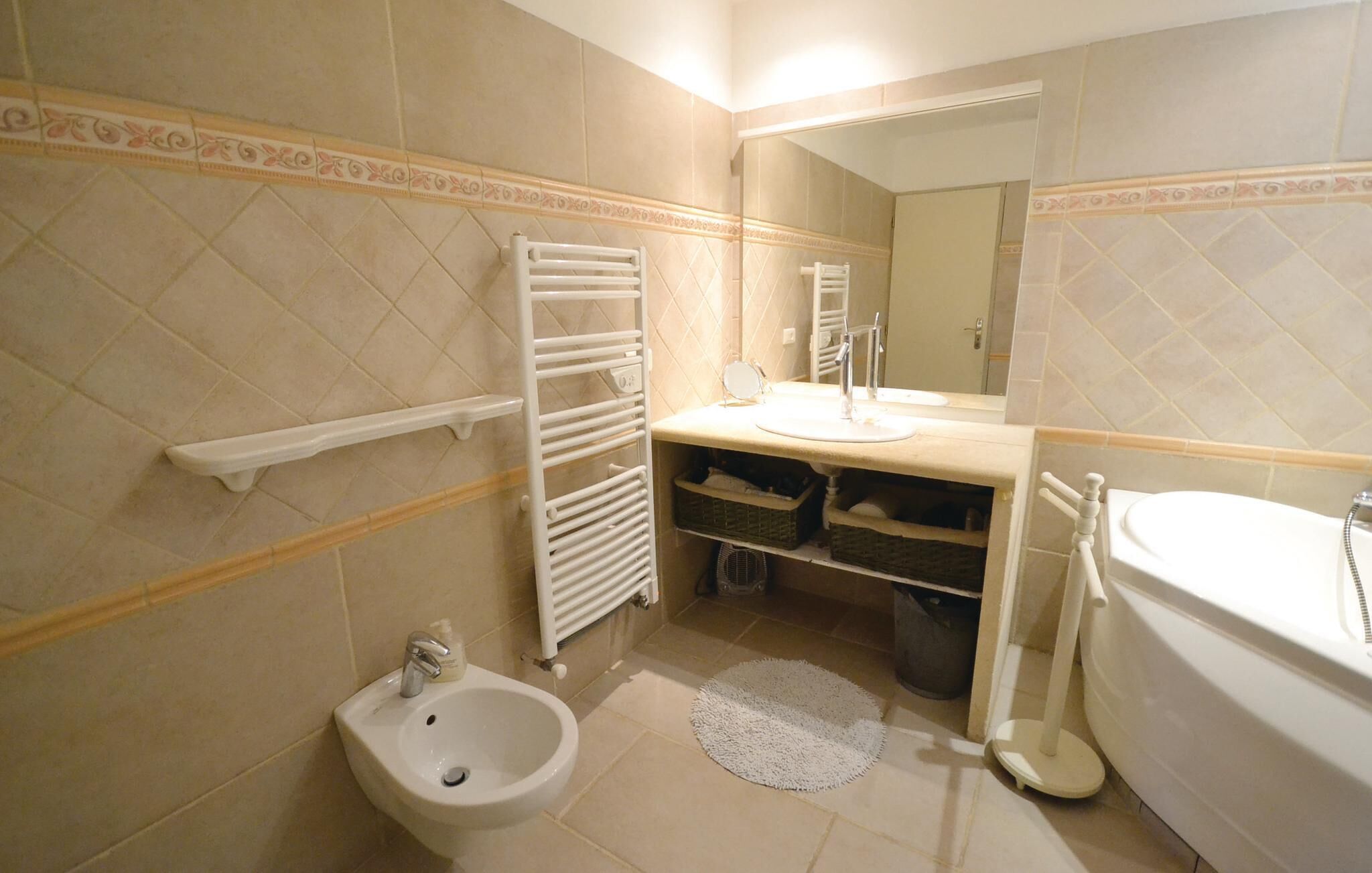 A bathroom with a bidet, a sink, a mirror, a towel rack, and a bathtub.