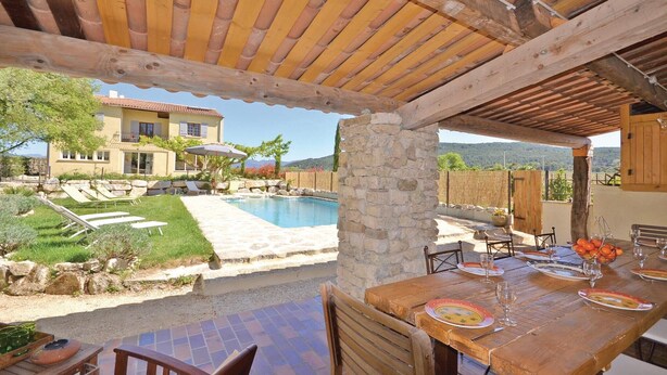 Un espacio al aire libre cubierto con piscina, paredes de piedra y una mesa de comedor lista para una comida.