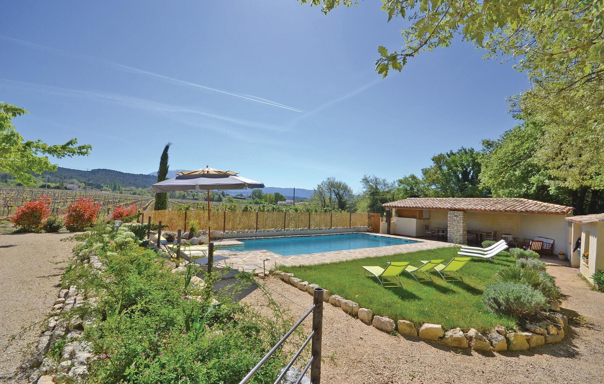 A pool area with a stone deck, surrounded by a well-maintained lawn and a variety of plants.