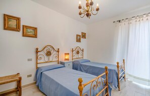 A bedroom with two beds, a chandelier, and framed pictures on the wall. - Cozy home in Camaiore (LU) (Camaiore (LU))