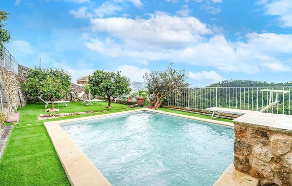 A rectangular swimming pool with a stone border, surrounded by a well-maintained lawn and trees. - Cozy home in Camaiore (LU) (Camaiore (LU))