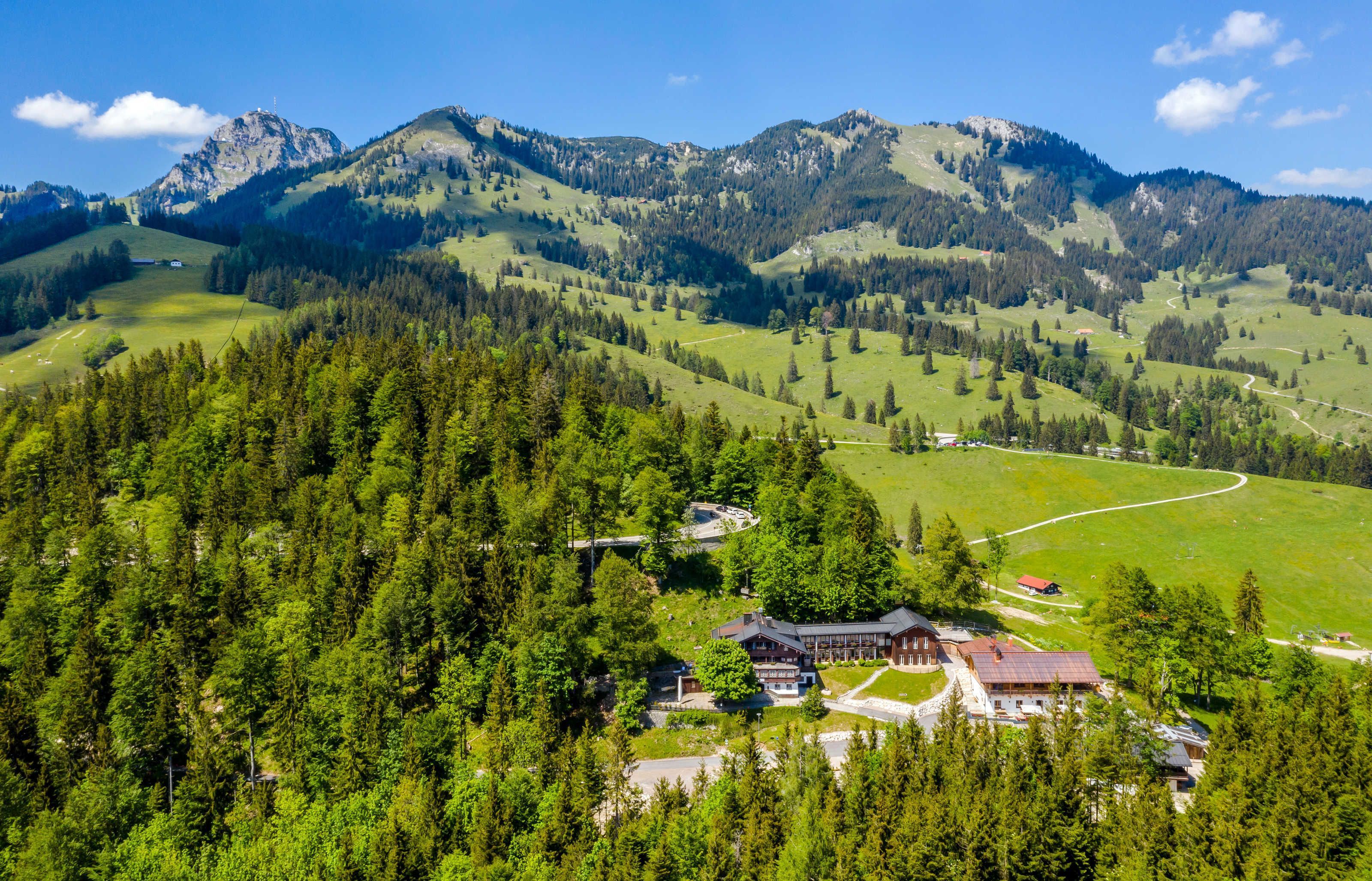 Eine Berghütte mit einem großen Gebäude, umgeben von dichtem Wald und Bergen.