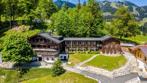 A large lodge with multiple buildings, surrounded by lush greenery and mountains. - Single room - Berghotel Sudelfeld (Bayrischzell)
