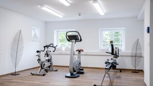 A gym with three stationary bikes, a treadmill, and a rowing machine. - Single room - Berghotel Sudelfeld (Bayrischzell)
