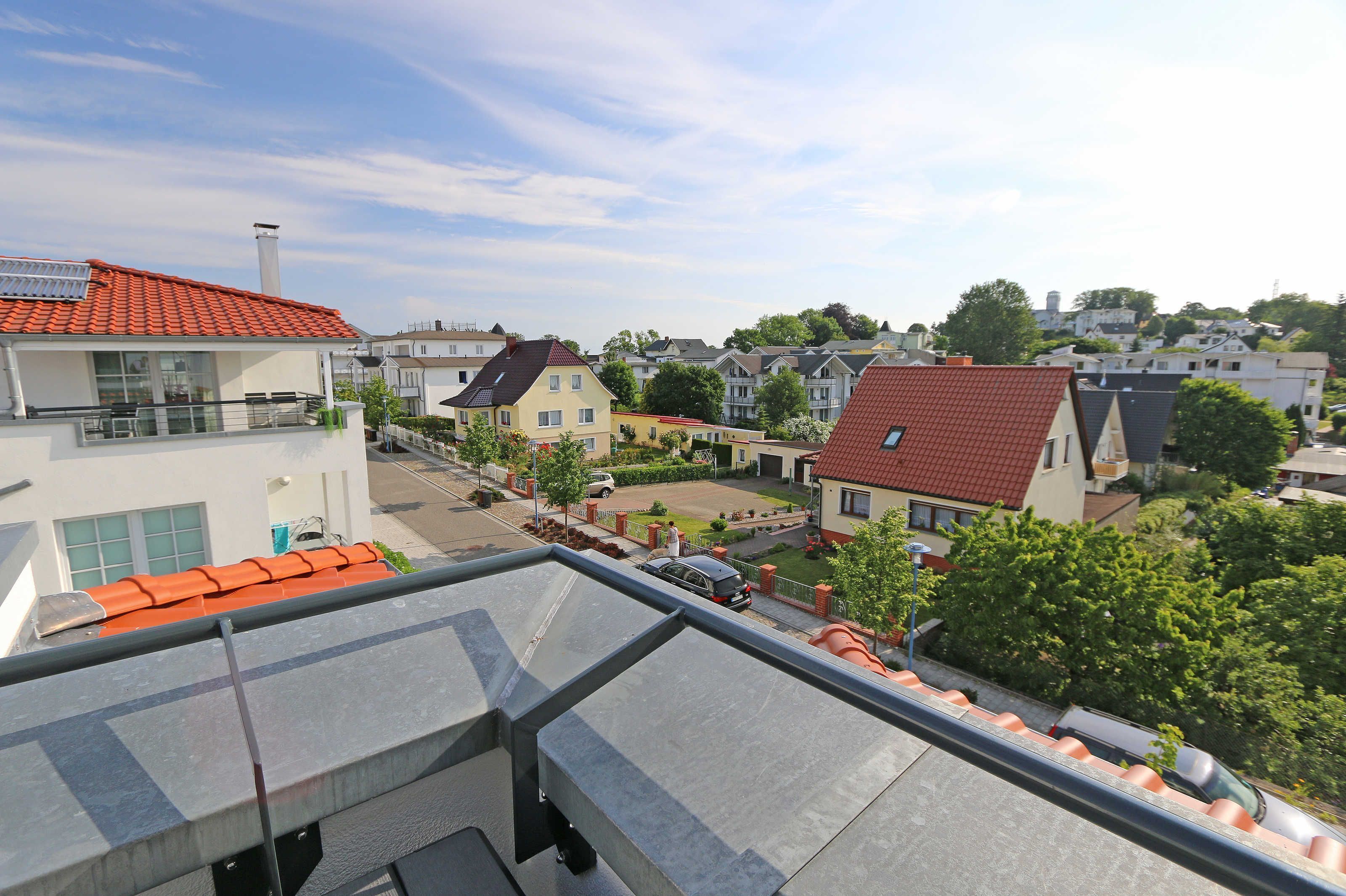 A residential area with houses, a clear sky, and a view of the neighborhood from a balcony.