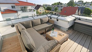 Una terrazza panoramica sul tetto con divano, tavolo e vista sulla città.