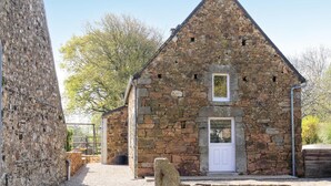 A stone building with a triangular roof, a white door, and a small window. - 2 bedroom amazing home in LA HAGUE (LA HAGUE)