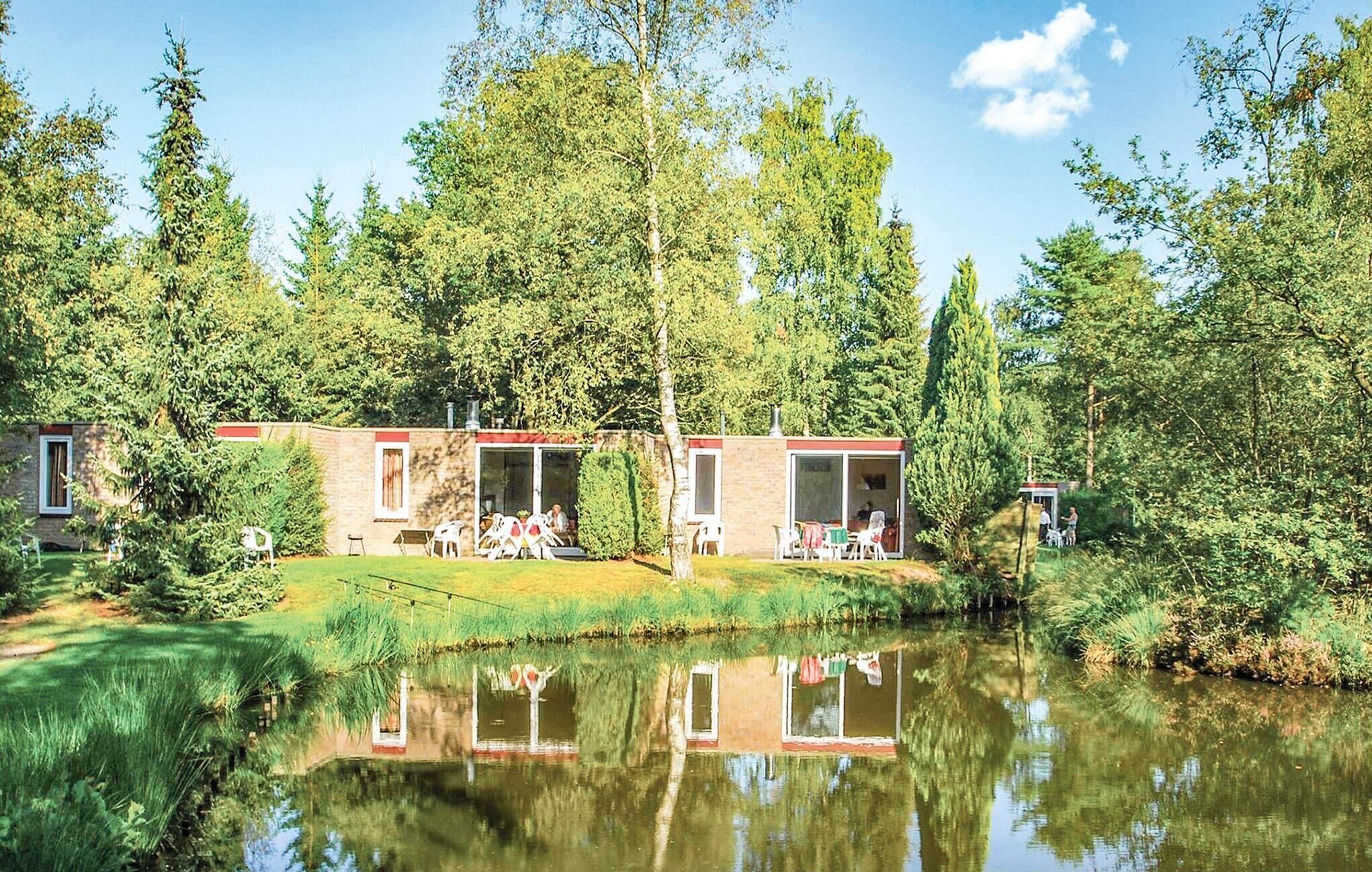 A lakeside cabin with two open patios, surrounded by dense forest and a calm lake.