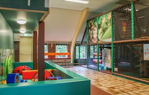 A children's play area with colorful play structures and a large window with a view of trees. - Cozy home in Vledder with WiFi (Vledder)