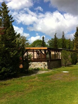 A cabin with a stone foundation, wooden beams, and a glass enclosure. - Holiday Bungalow Daniela - Bungalow Daniela (Eggesin)