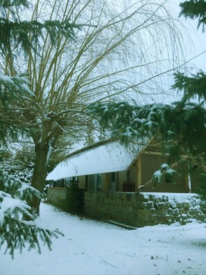 Un edificio de piedra con techo nevado, rodeado de árboles.