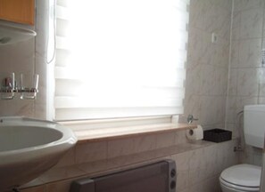 A bathroom with a sink, toilet, and window.