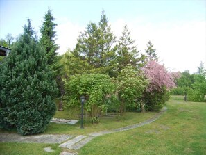 Un jardín con un camino de piedra, varios árboles y un farol.
