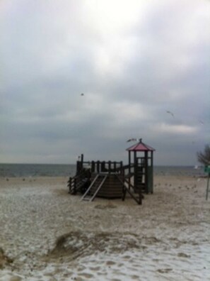 Ein Strand mit einer Holzkonstruktion, möglicherweise einer Rettungswache, und einer Treppe, die darauf führt.