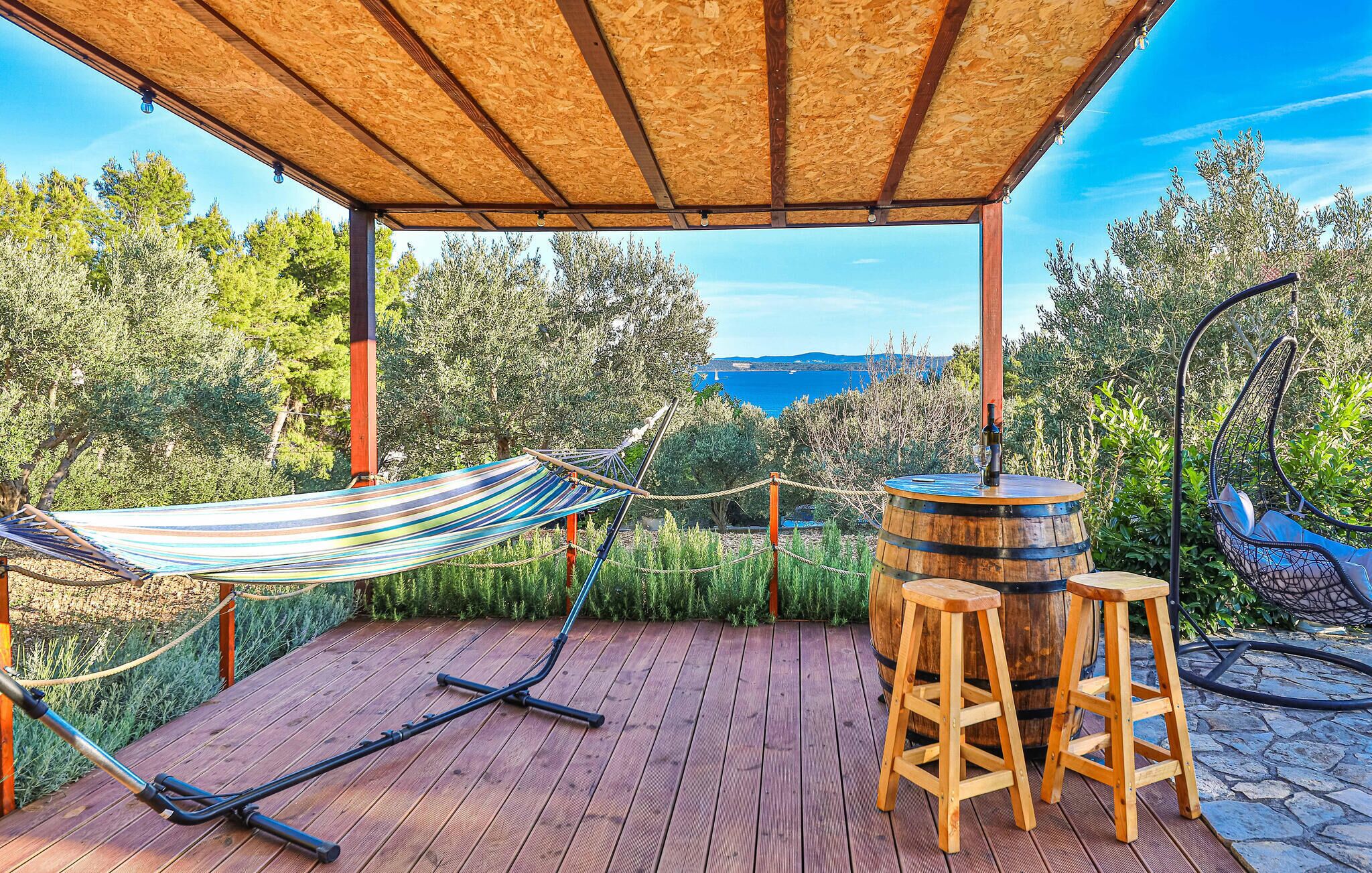 A wooden deck with a hammock, stools, and a barrel.