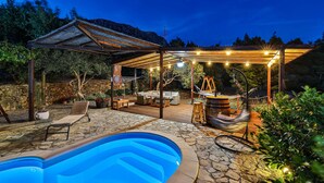 A poolside area with a pergola, seating, and a bar.