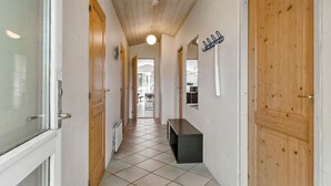 En gang med trædøre, en bænk og et spejl på væggen.