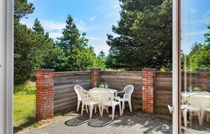 Eine Terrassenfläche im Freien mit einer Ziegelwand, weißen Plastikstühlen und einem Tisch.