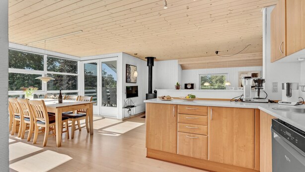 A modern kitchen with wooden cabinets, a large island, and a dining area with a table and chairs. - Lovely home in Hejls with WiFi (Hejls)