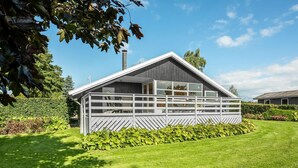 A modern house with a sloped roof, large windows, and a fenced patio area. - Lovely home in Hejls with WiFi (Hejls)