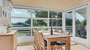 A dining area with a wooden table and chairs, large windows, and a view of greenery outside. - Lovely home in Hejls with WiFi (Hejls)