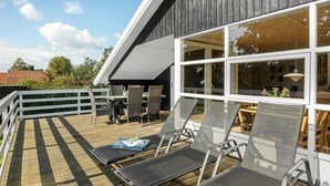 A deck with lounge chairs and a table, overlooking a garden and a building with large windows. - Lovely home in Hejls with WiFi (Hejls)