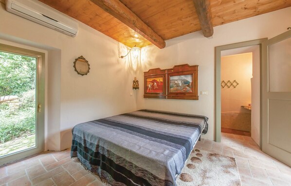Een slaapkamer met een bed, een spiegel, een aan de muur bevestigd schilderij en een deur naar een andere kamer.