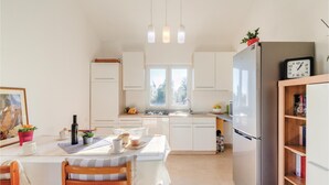 Een moderne keuken met witte kasten, een roestvrijstalen koelkast en een raam dat voor natuurlijk licht zorgt.