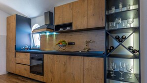 Eine moderne Küche mit Holzausbau, einer integrierten Weinkühlbox und einer Obstschale auf der Arbeitsfläche.