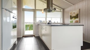Una cocina moderna con una isla grande, armarios blancos y vistas al exterior.
