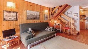 Un salon confortable avec un canapé, un téléviseur et un escalier menant à l’étage supérieur.