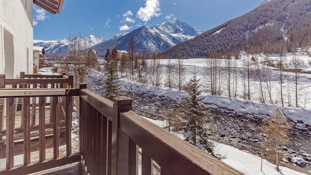 Un balcon offrant une vue sur des montagnes enneigées et un ciel dégagé.