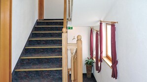 A staircase with a dark carpeted floor and wooden handrails, leading to an upper floor. - gemuetliche Ferienwohnung (Kappl)