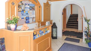 A reception area with a wooden counter, a mirror, and a bulletin board with travel brochures. - gemuetliche Ferienwohnung (Kappl)