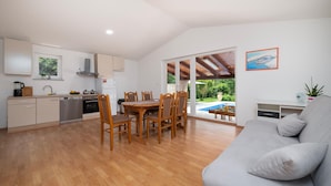 A modern kitchen with wooden cabinets, a dining area with a table and chairs, and a grey sofa. - Pet friendly home in Labin (Labin)