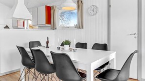 A modern kitchen with white cabinets, a hanging pendant light, and a window with curtains.