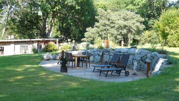 A patio with a stone wall, a wooden table, and chairs.
