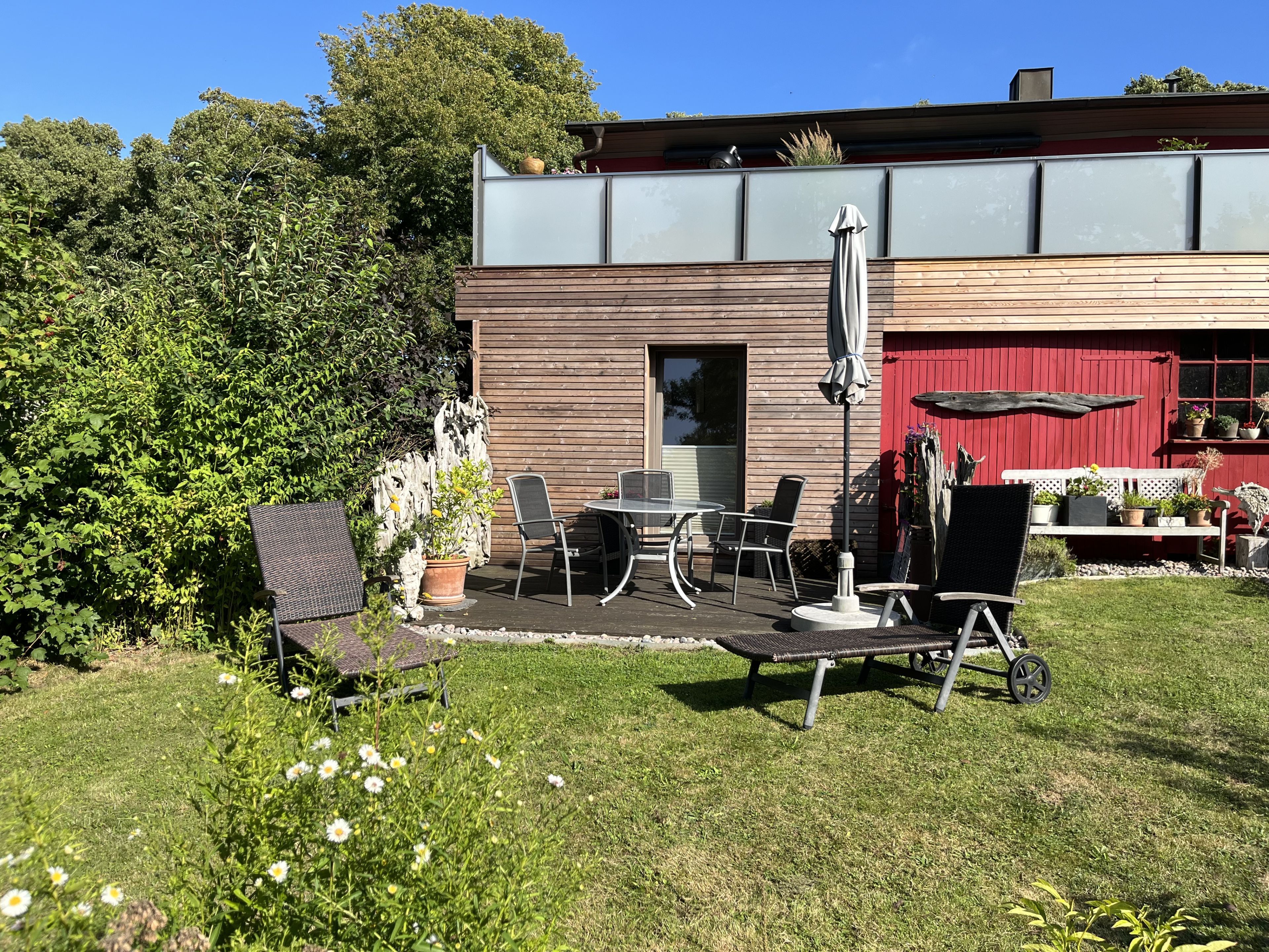 Eine moderne Terrassenanlage mit Esstisch, Bank und Topfpflanzen.