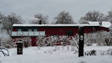 Ein rotes Gebäude mit Balkon, umgeben von schneebedeckter Vegetation.