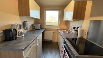A compact kitchen with a built-in oven, a kettle, a toaster, and a sink.