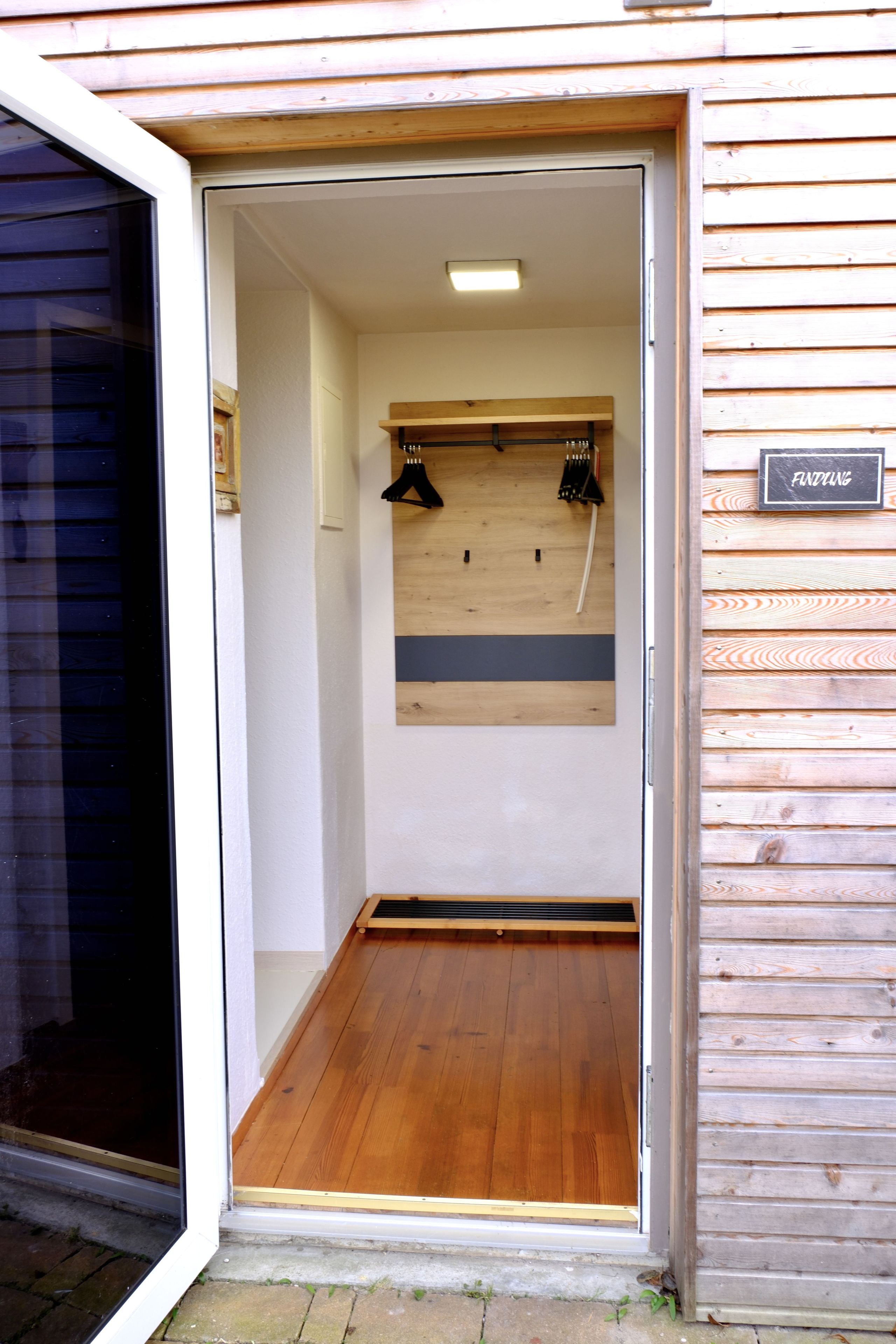 Interior de madera con una puerta que da a una habitación, un letrero en la pared y piso de madera.
