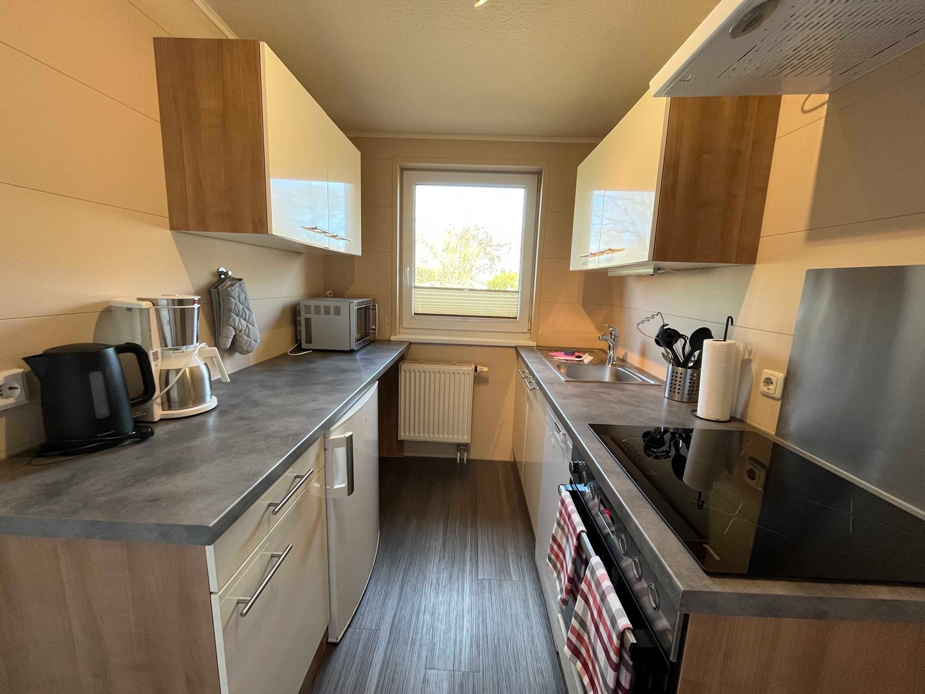A compact kitchen with a built-in oven, a kettle, a toaster, and a sink.