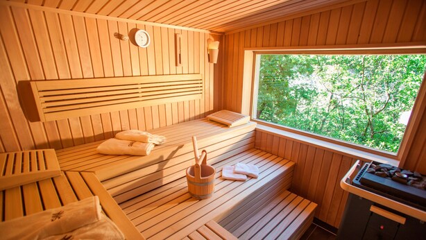 A wooden sauna with benches, a heater, and towels.