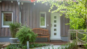 A wooden house with a porch, a bench, and a door.