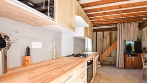 Une cuisine avec des meubles en bois, une cuisinière à gaz et un four à micro-ondes. Un escalier mène à une autre pièce.