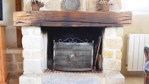 Une cheminée en pierre avec un paravent en métal, une cheminée en bois rustique et des paniers décoratifs.