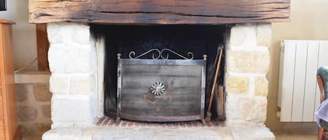 A stone fireplace with a metal screen, a rustic wooden mantel, and decorative baskets.