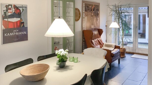 Un coin repas avec une table ronde, des chaises, un vase de fleurs et une lampe.