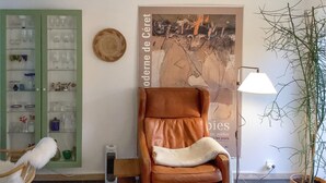 Une pièce comprenant un fauteuil en cuir marron, un meuble vert contenant de la verrerie, une affiche accrochée au mur, une lampe et une plante en pot.